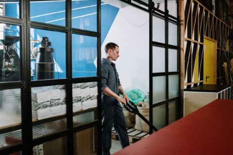 A man in uniform operates machinery in a coffee roastery, highlighting industrial work.